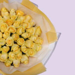 A large bouquet of yellow roses wrapped in yellow paper with a white ribbon.